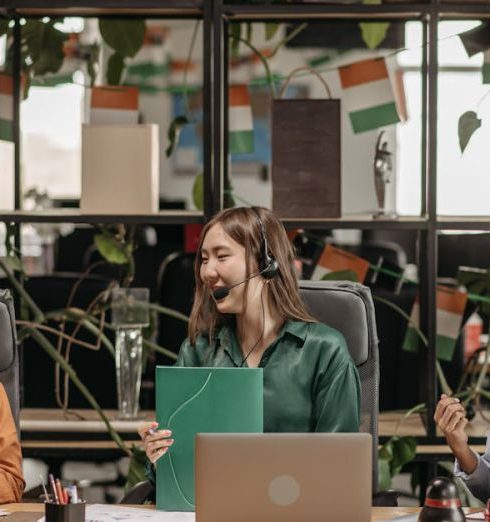 International Office - Three women with headsets working together in a vibrant, plant-filled modern office space.