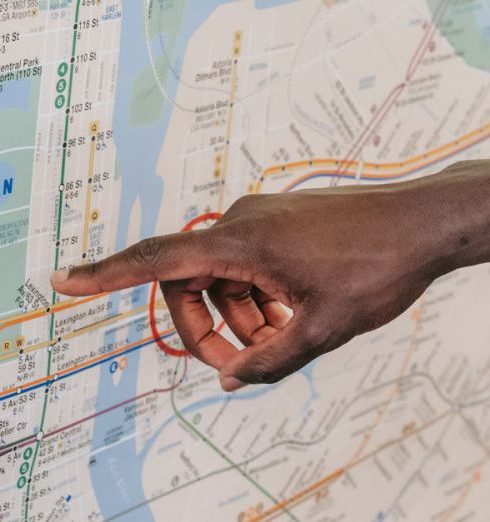 Localization - Close-up of a hand pointing at a Manhattan subway map, emphasizing transportation guidance.