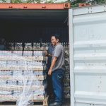 Exporting - Two men load products into a shipping container in Ipoh, Malaysia, showcasing logistics.