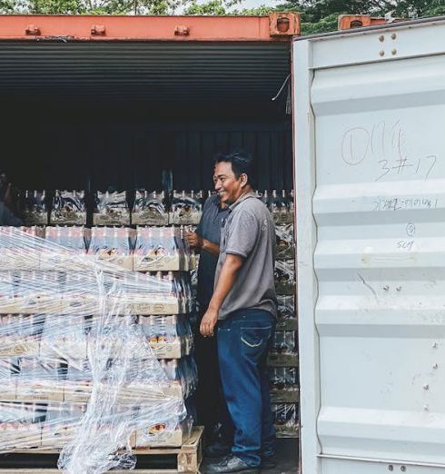 Exporting - Two men load products into a shipping container in Ipoh, Malaysia, showcasing logistics.