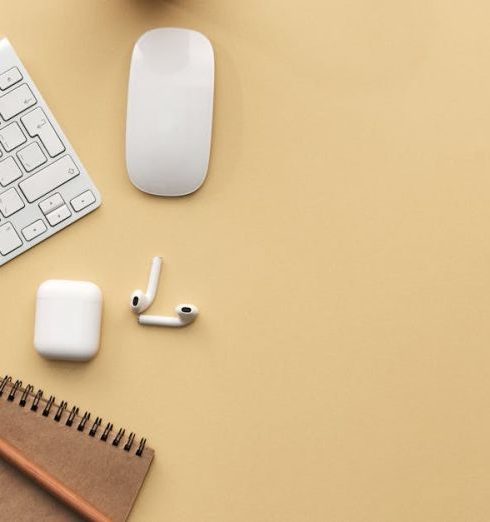 Technology - A minimalist workspace flat lay with keyboard, mouse, notebook, and succulent on a beige background.