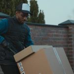 Distributors - Courier loading cardboard box into a van outdoors, showcasing logistics work.