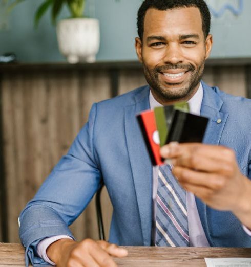 Payment Solutions - Smiling African American man in a suit holding credit cards at a business desk.