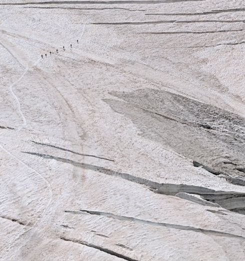 Remote Teams - Stunning aerial view of hikers on the vast Aletsch Glacier in Switzerland.