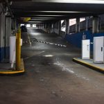 Entry Barriers - Entrance ramp of an underground parking garage with barriers and dim lighting, depicting urban infrastructure.