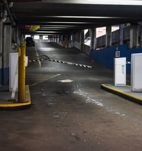 Entry Barriers - Entrance ramp of an underground parking garage with barriers and dim lighting, depicting urban infrastructure.