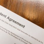 Intellectual Property - Detailed close-up of a patent agreement document on a polished wooden table.