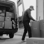 Supply Chain Management - Delivery driver unloads packages from a van, organizing shipments outdoors.