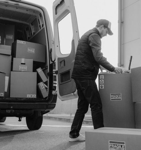 Supply Chain Management - Delivery driver unloads packages from a van, organizing shipments outdoors.