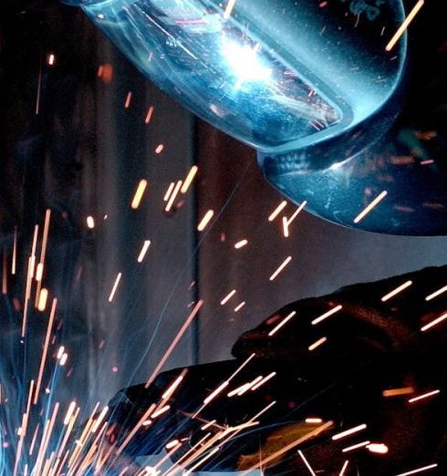 Manufacturing - A focused welder works with metal in an industrial setting, creating vibrant sparks.