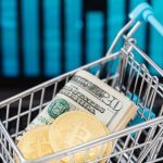 Market Diversification - Symbolic image of cryptocurrency and cash in a shopping cart on a laptop, representing digital finance and trading.