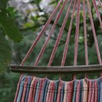 Hammocks - Striped hammock hanging outdoors among vibrant greenery and tall trees.