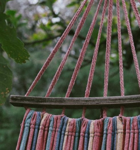 Hammocks - Striped hammock hanging outdoors among vibrant greenery and tall trees.