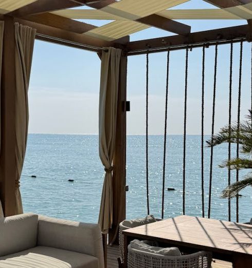 Shaded Area - Elegant beachfront outdoor lounge under a pergola with ocean view.