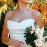 Outdoor Loveseats - A beautiful bride in a strapless gown holding a bouquet amidst vibrant autumn foliage.