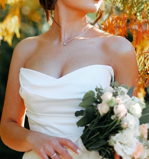 Outdoor Loveseats - A beautiful bride in a strapless gown holding a bouquet amidst vibrant autumn foliage.