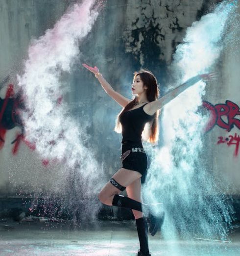 Pest-Free - Young woman dances with colored powder against urban graffiti backdrop, creating vibrant energy.