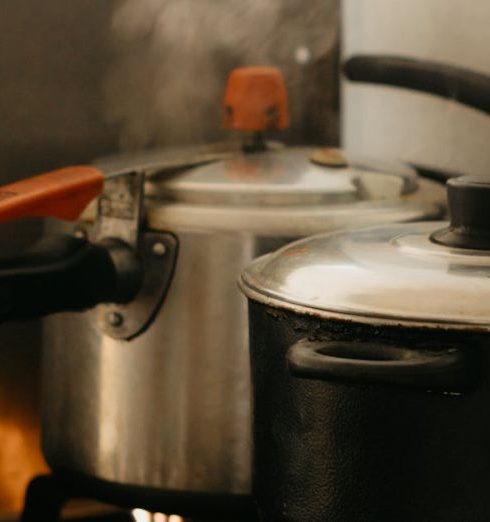 Pressure Cooker - A stove with two pots on it and steam coming out of them