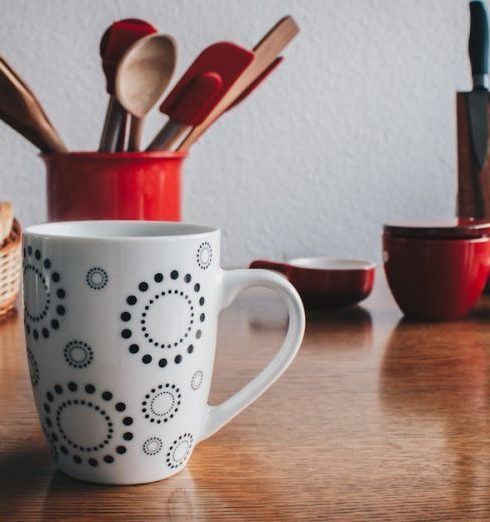 Knives - Mug in Front of Breads Beside Spatulas on Table