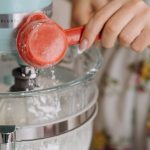 Stand Mixer - A Person Putting Flour in a Batter Mixture