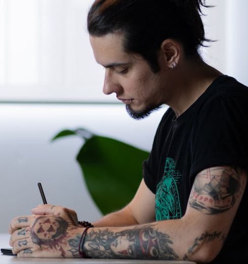 Minimalist Office - Concentrated tattooed artist drawing in a modern, minimalist workspace with natural light.