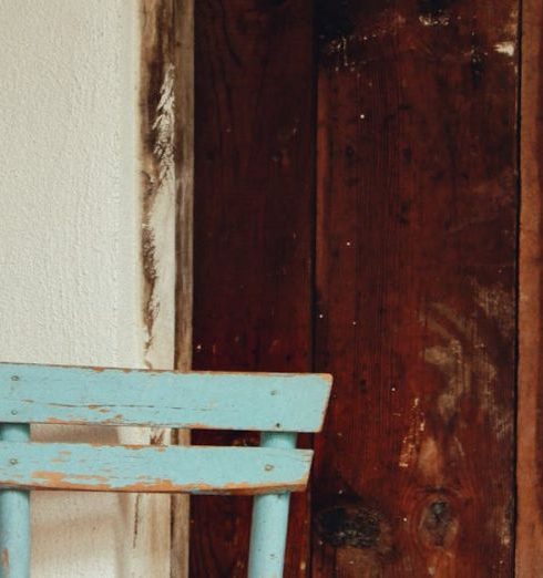 Minimalist Furniture - A rustic blue chair with a worn look sits against a vintage wooden wall.