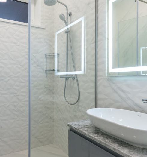 Walk-In Shower - Stylish mirror illumination shining in bathroom above sink with faucet and shower cabin