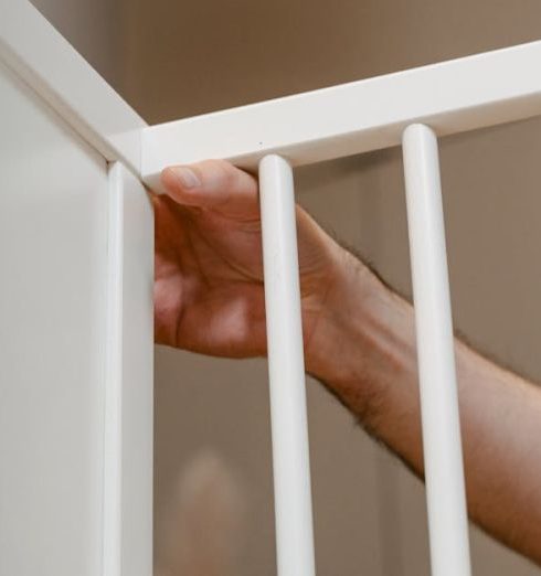 Childproofing - A Hand Touching the Edge of a Wooden Fence