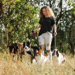 Multiple Pets - Woman with dogs walking on grassy terrain