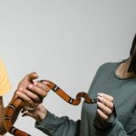 Pet Anxiety - A Fearful Woman Having Ophidiophobia while Standing next to a Man Who's Holding a Snake