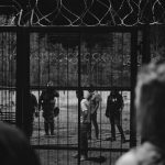 Security Fences - People Standing Near the Metal Fence