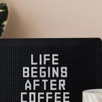 Pegboards - Light up letter message board reading Life Begins After Coffee and ceramic coffee cup on table with green pot plant near pastel pink wall