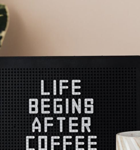 Pegboards - Light up letter message board reading Life Begins After Coffee and ceramic coffee cup on table with green pot plant near pastel pink wall