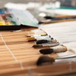 Craft Supplies - A collection of paint brushes and watercolor set on a bamboo mat, ready for artistic creation.