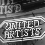 Mid-Century Design - Retro neon sign of United Artists with classic car backdrop and reflections, in black and white.