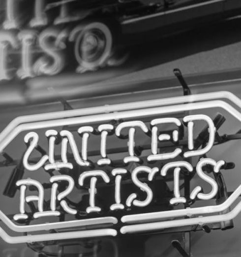 Mid-Century Design - Retro neon sign of United Artists with classic car backdrop and reflections, in black and white.