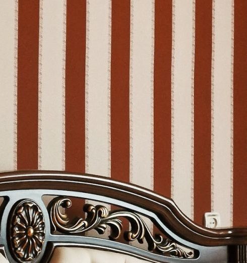 Traditional Furniture - Luxurious bedroom featuring a carved wooden headboard and striped wallpaper for a classic look.