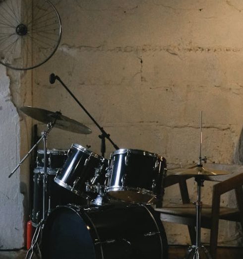 Industrial Loft - Modern drum set placed on wooden floor in contemporary studio with decorations and shelves on white shabby stone wall with lamp