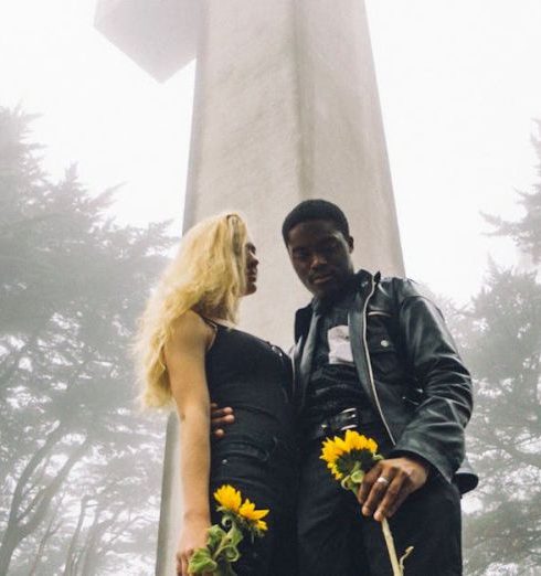 Year-Round Landscape - Photo of Man and Woman Standing Beside Cross Monument