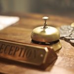 Registration - Old fashioned golden service bell and reception sign placed on wooden counter of hotel with retro interior