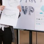 Crowdfunding - A young woman gives a startup presentation with charts and graphs on a flipchart.