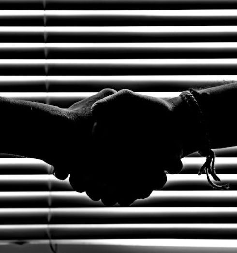 Partnership - Silhouette of two people shaking hands symbolizing partnership and trust.