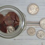 Finances - Top view of a jar filled with coins placed on a wooden table, depicting savings.