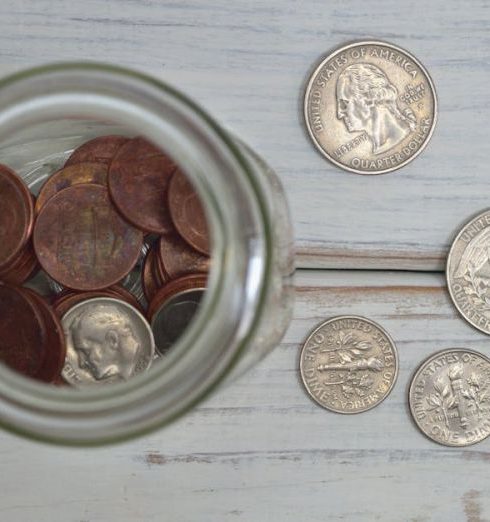 Finances - Top view of a jar filled with coins placed on a wooden table, depicting savings.