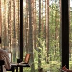 Freelancers - A man and woman working from home in a scenic cabin surrounded by forest.