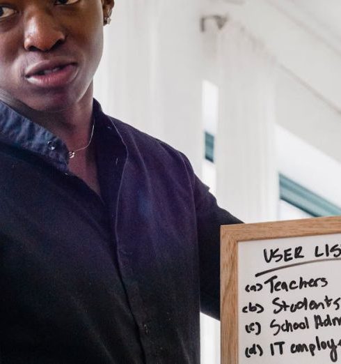 Sales Funnel - Confident man presenting business concepts on a whiteboard during a meeting indoors.