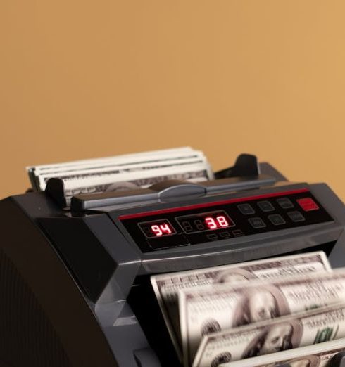 Revenue - Electronic money counter processing US dollars on a neutral background.