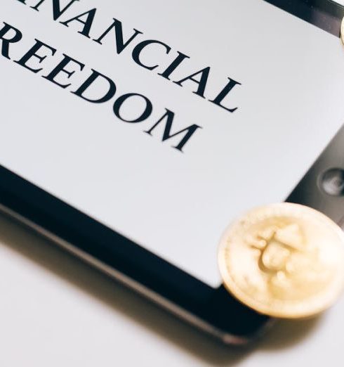 Savings Account - Coins are scattered around a digital tablet displaying 'Financial Freedom', symbolizing cryptocurrency wealth.