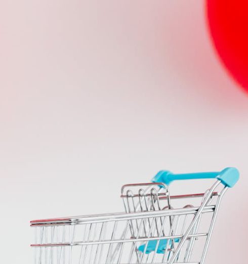 Financial Ratios - Mini shopping cart with red percentage balloons on a white background, symbolizing sales.