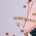 Startup Costs - Flat lay of a small business planning scene with coins, smartphone calculator, and letter tiles.